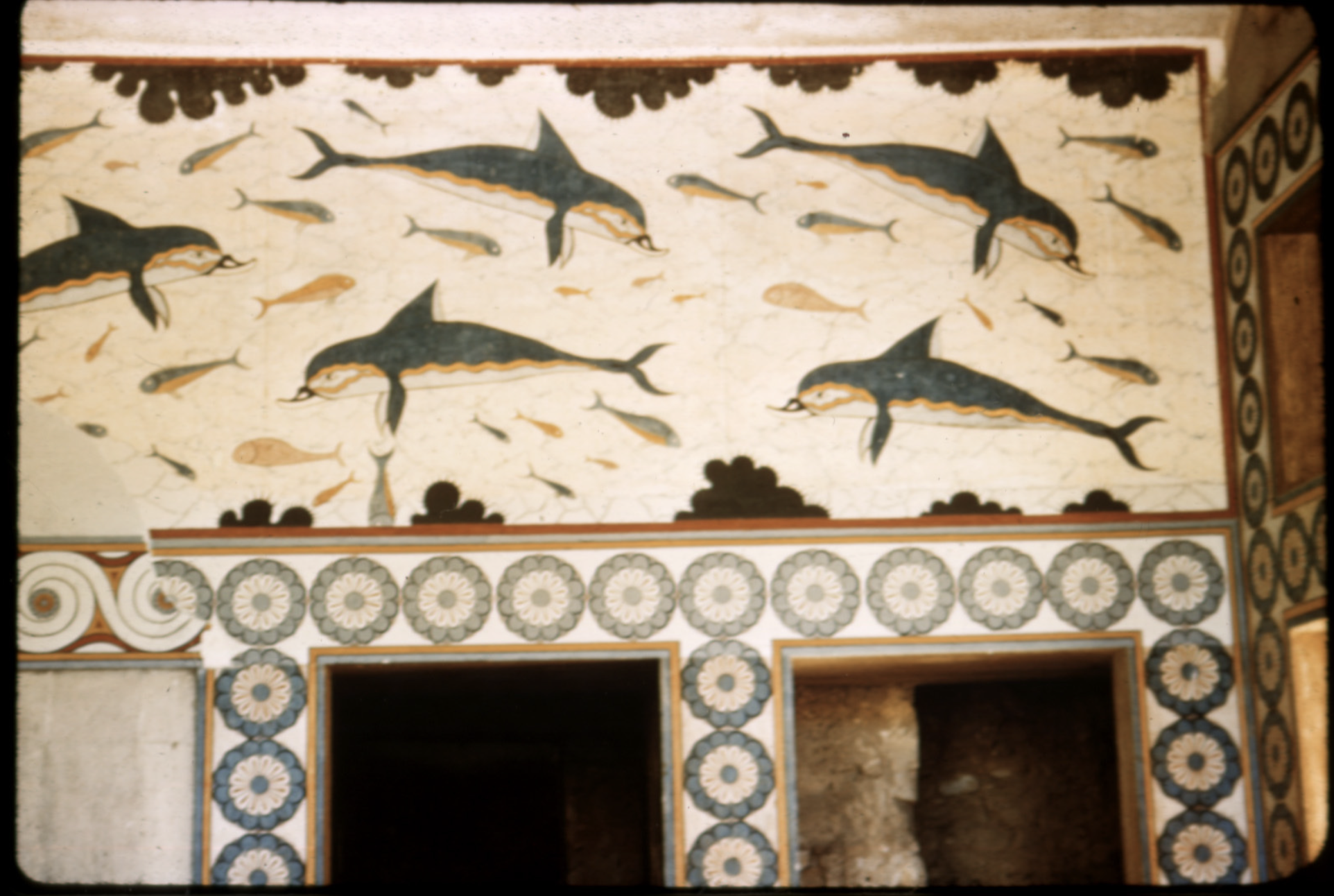 This image depicts the reconstruction of the dolphin fresco of the queen’s megaron at Knossos. The fresco shows dolphins as well as other marine life swimming around with decoration around the borders. Marine life as well as scenes in nature were very popular to use as decoration on walls so it is often scene in Greek homes, not just in the megaron at Knossos. Even though there is no evidence that the room in which this fresco is shown was meant for the queen, it is still an example of the kind of art women would be exposed to in their own home. It was very common to see frescos on the wall of homes all over Greece so it is a part of Greek art that even a woman who only stays home can enjoy this art on their walls.  