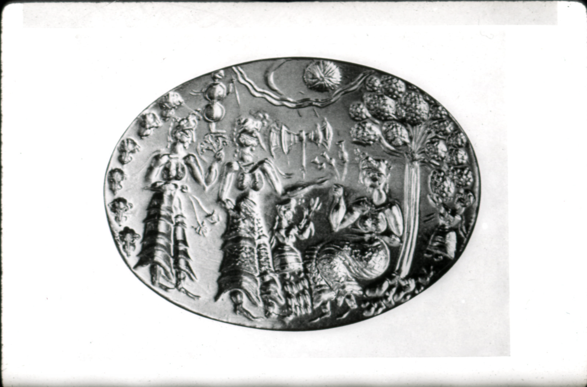 This piece is from a Minoan seal ring used as a form of signature or identification. There are three women depicted in the seal, the two on the left are standing while the other woman on the right is seated. There is also a tree to the right of the third woman as well as floating objects, or decoration, around the seal as well. The women in the seal are Minoan based on what they are wearing but could also possibly be divine women since the Minoans tend to worship multiple goddesses. Although it is not typical for a woman to be wearing a seal ring, it still falls under the category of jewelry. Minoan women are depicted wearing lots of jewelry in paintings and mosaics, so they would be able to appreciate the art on their jewelry since they interact with it in their lives.  